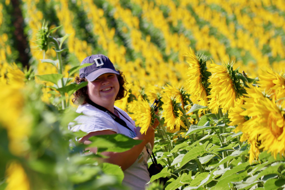 Hannah smiling among the sunflowers